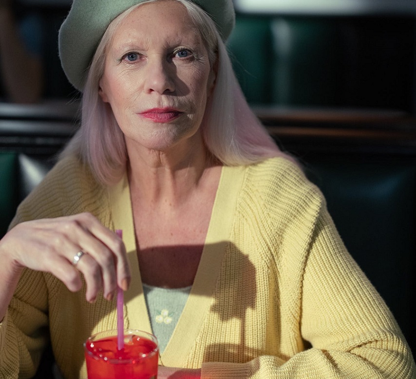picture of a woman wearing a yellow cardigan drinking red beverage  