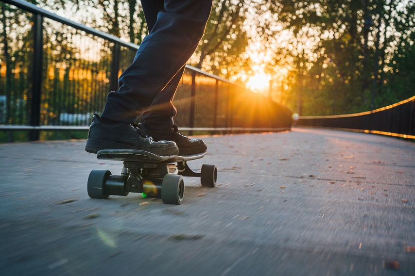 person riding electric skateboard at sunset 
