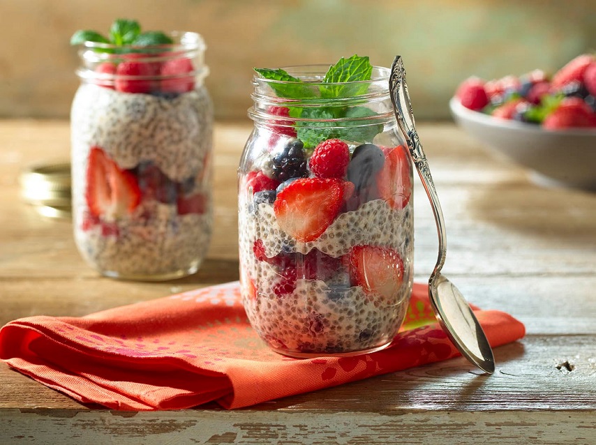 chia pudding with fruit in jars on wooden table 